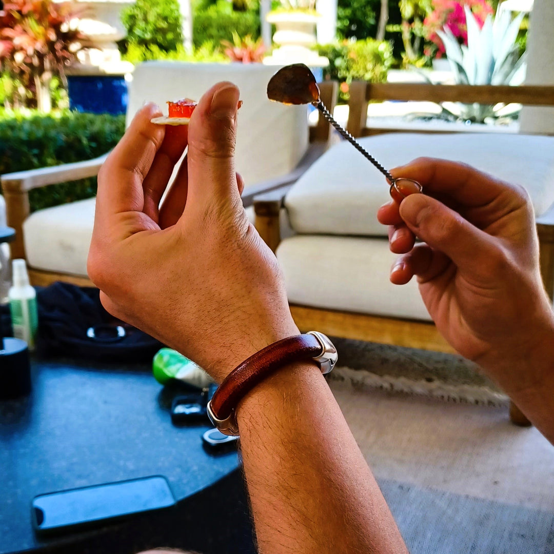 A person preparing a cracker to eat and holding a spoon outdoors with greenery in the background. Cobo bracelet lifestyle photo.