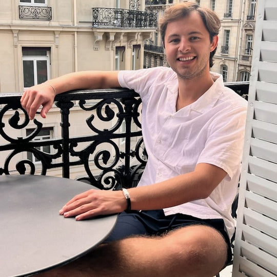 Man sitting at a table on a balcony with a cityscape background. Cobo bracelet lifestyle photo