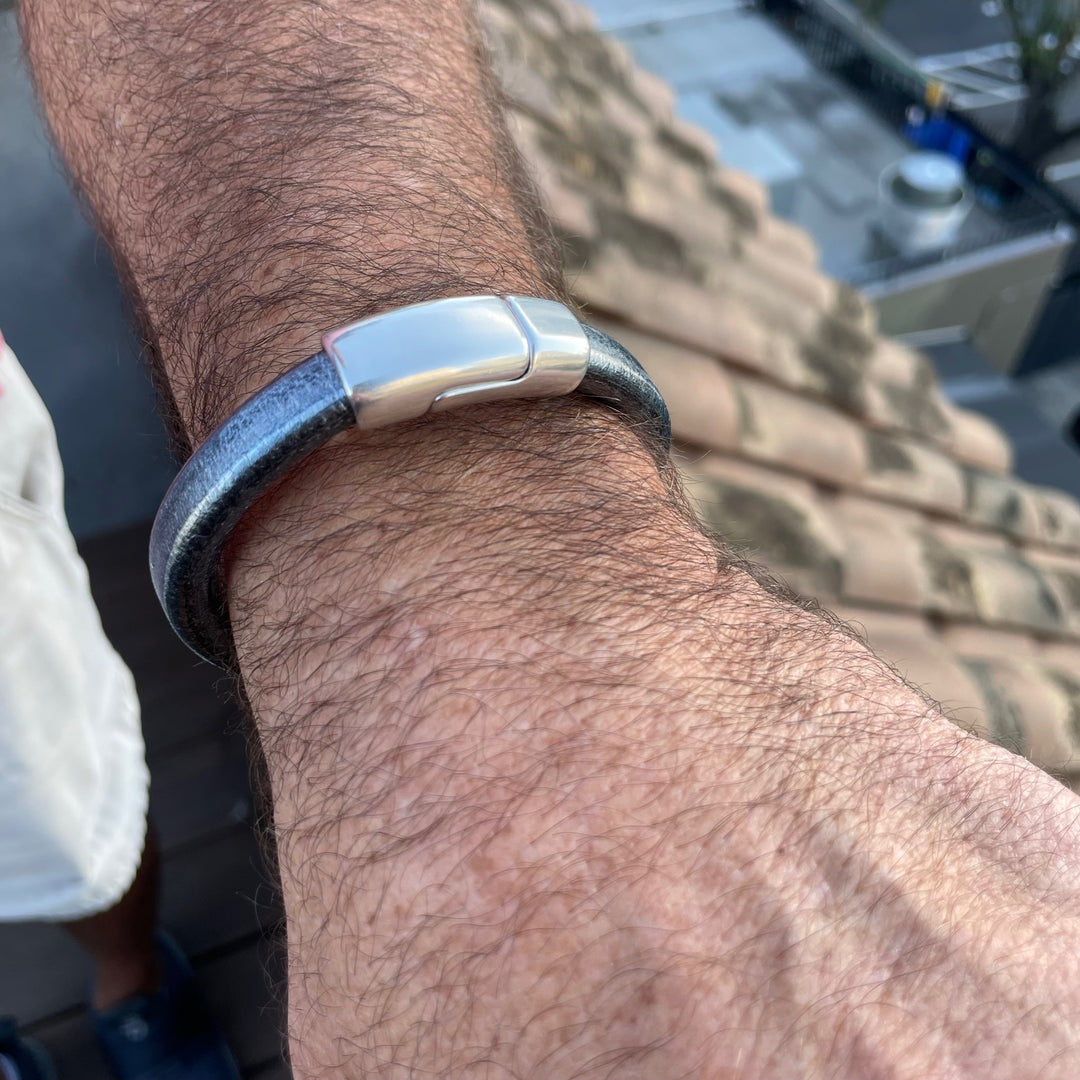 Close-up of a wrist wearing a silver-black leather bracelet with a silver clasp. Cobo bracelet lifestyle photo.