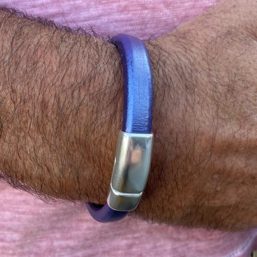 Close-up of a wrist wearing a blue leather Cobo bracelet with a silver clasp. Cobo bracelet lifestyle photo.