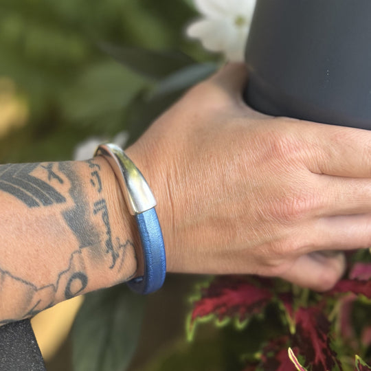 Hand wearing a blue bracelet with a blurred background