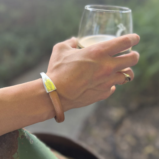 Hand holding a glass of white wine with a blurred natural background