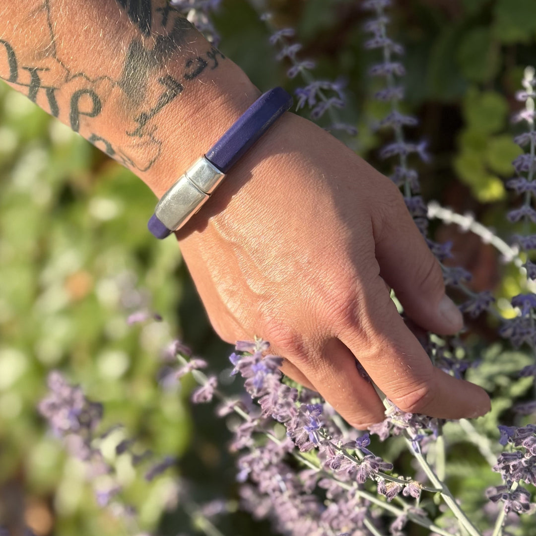 Hand with a purple bracelet touching lavender flowers