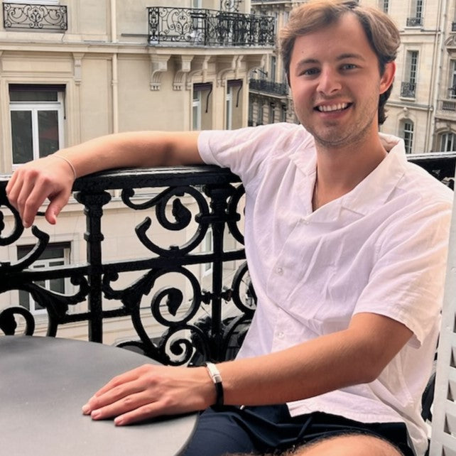 Man sitting on a balcony with a building in the background