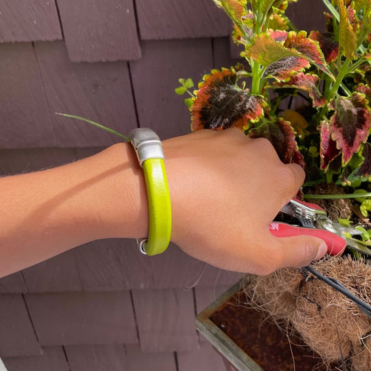 Bright lime green bracelet worn on a person pruning a plant.